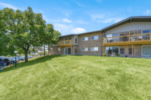 Exterior brick Residential buildings, large field of grass, meticulous landscaping, lush foliage, photo taken a sunny day.