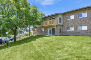 Exterior brick Residential buildings, large field of grass, meticulous landscaping, lush foliage, photo taken a sunny day.