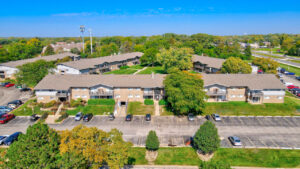Aerial Exterior of brick Residential buildings, Meticulous landscaping, lush foliage, parking around residential buildings.