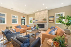 Interior Clubhouse Lounge area, 2 large couches, 2 lounge chairs, contemporary rustic decor, stone fireplace, abstract art on the walls, wood floors.