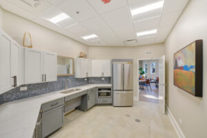 Interior Community Kitchen, stone floors, stone countertops with white and gray cabinets, stainless steel appliances.