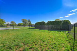 Exterior Dog park, Fenced in, adjacent to sport court, meticulously groomed grounds, lush foliage, photo taken on a sunny day