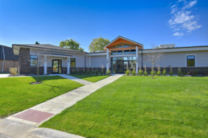 Exterior Clubhouse, meticulous landscaping, lush foliage, photo taken on a sunny day.