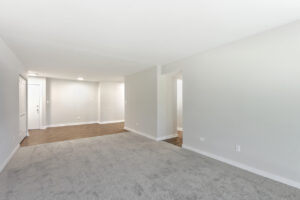 Interior Unit Living room, Neutral toned walls and carpeting, wood floors in the hallway, sliding glass doors to balcony .