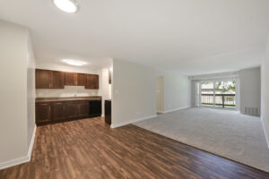 Interior Unit Kitchen, wood floors, brown cabinetry, black appliances, stainless steel sing, carpeting in the living room.