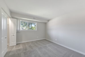 Interior Unit Bedroom, Neutral toned carpeting and walls, double window on wall.