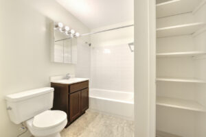 Interior Unit Bathroom, Tile floor, dark brown cabinets, white walls, stone countertop, linen closet, bathtub/shower, well lit vanity mirror.